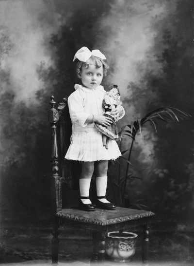 Studio portrait of a young girl standing on a chair.  Family name Charlesworth.