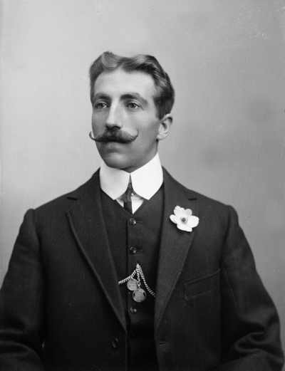 Studio portrait of a young man with a handle-bar moustache.  Family name possibly Knorr.