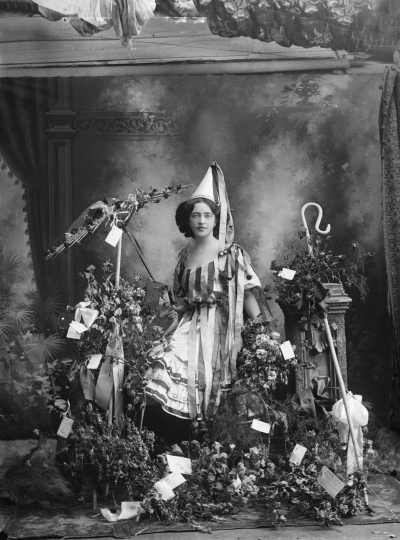 A young woman in costume standing amongst  flowers.  Family name Cullen or Cutler.