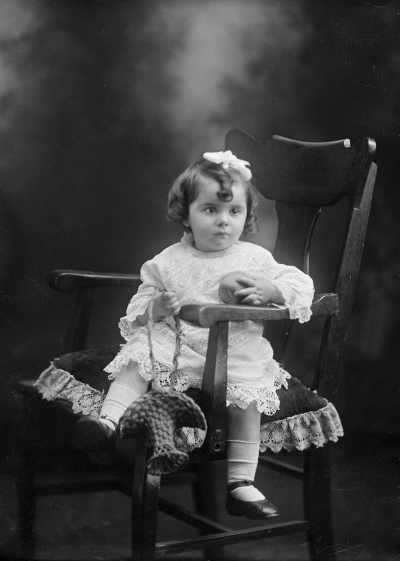 Studio portrait of a young girl seated in a carver chair.  Family name Cresswell.