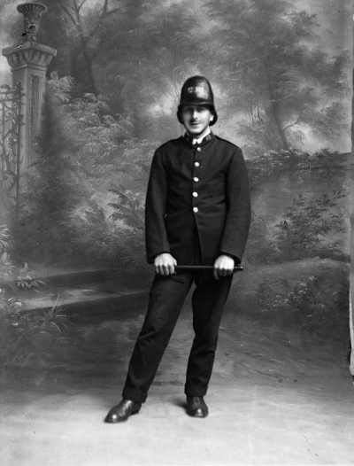Studio portrait of a young man dressed in a police uniform. Family name Trembath.