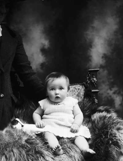 Studio portrait of a baby wearing a knitted dress.   Family name McCoy.