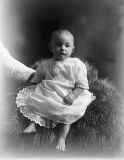 Studio portrait of a baby wearing a dress.  Family name Cleary.