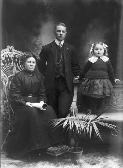 Studio portrait of a woman, a young man and a young girl.  Family name White.