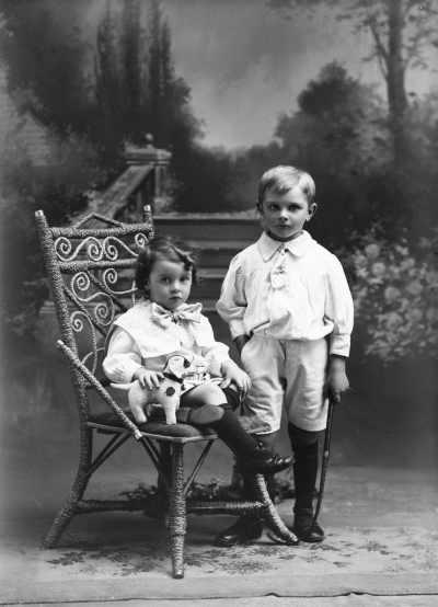 Studio portrait of two children holding toys.   Family name Hanley.