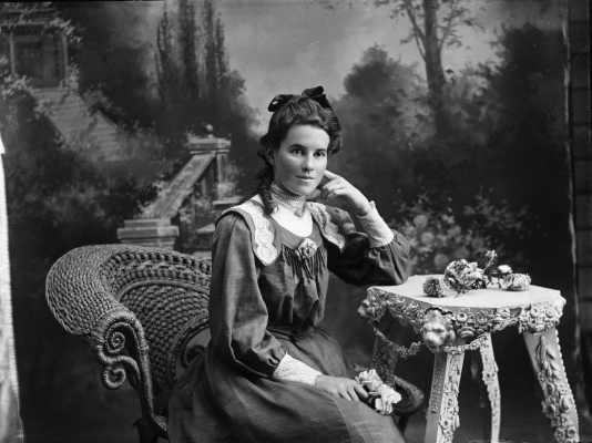 Studio portrait of a young woman holding a rose.  Family name Mills.