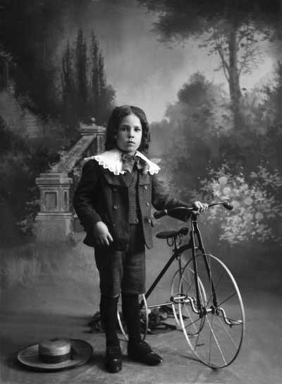 Studio portrait of a boy with a tricycle. Family name Robert or Rolent.