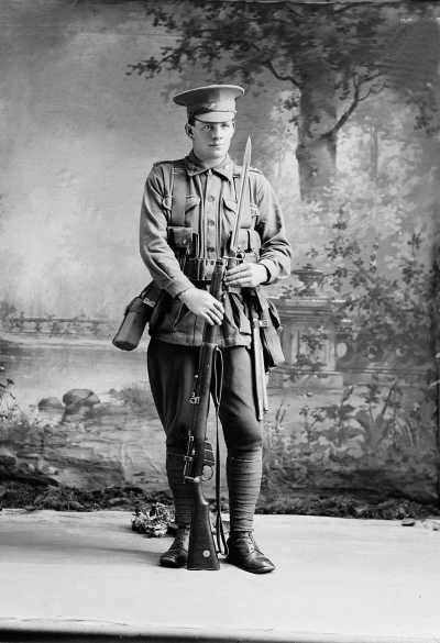 Studio portrait of a man in an Australian Army uniform holding a rifle.  Family name &lsquo;Wright.