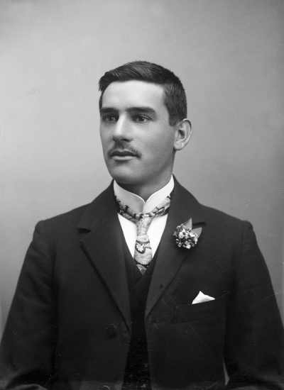 A half-length indoor portrait of Mr. C. Williams wearing a paisley tie.
