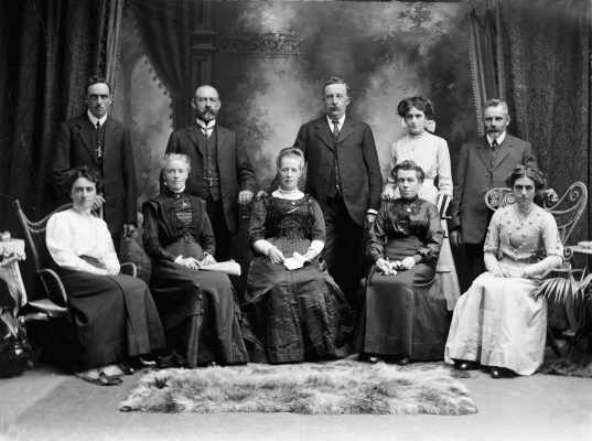 An unidentified posed group of ten adults in a photograhic studio.