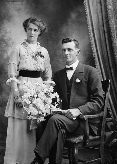 Studio portrait of a woman standing alongside a seated man.  Family name Foster.