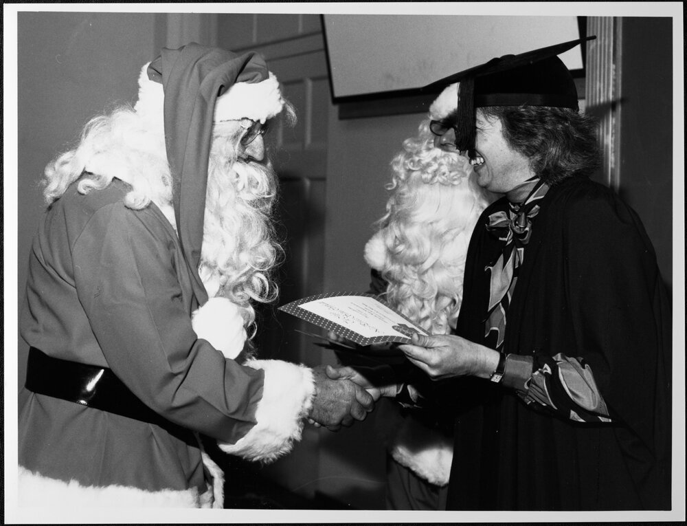 Santa School. Peggy McMurray (Personnel Services) presents graduation certificates to Santas at 1987 Santa School