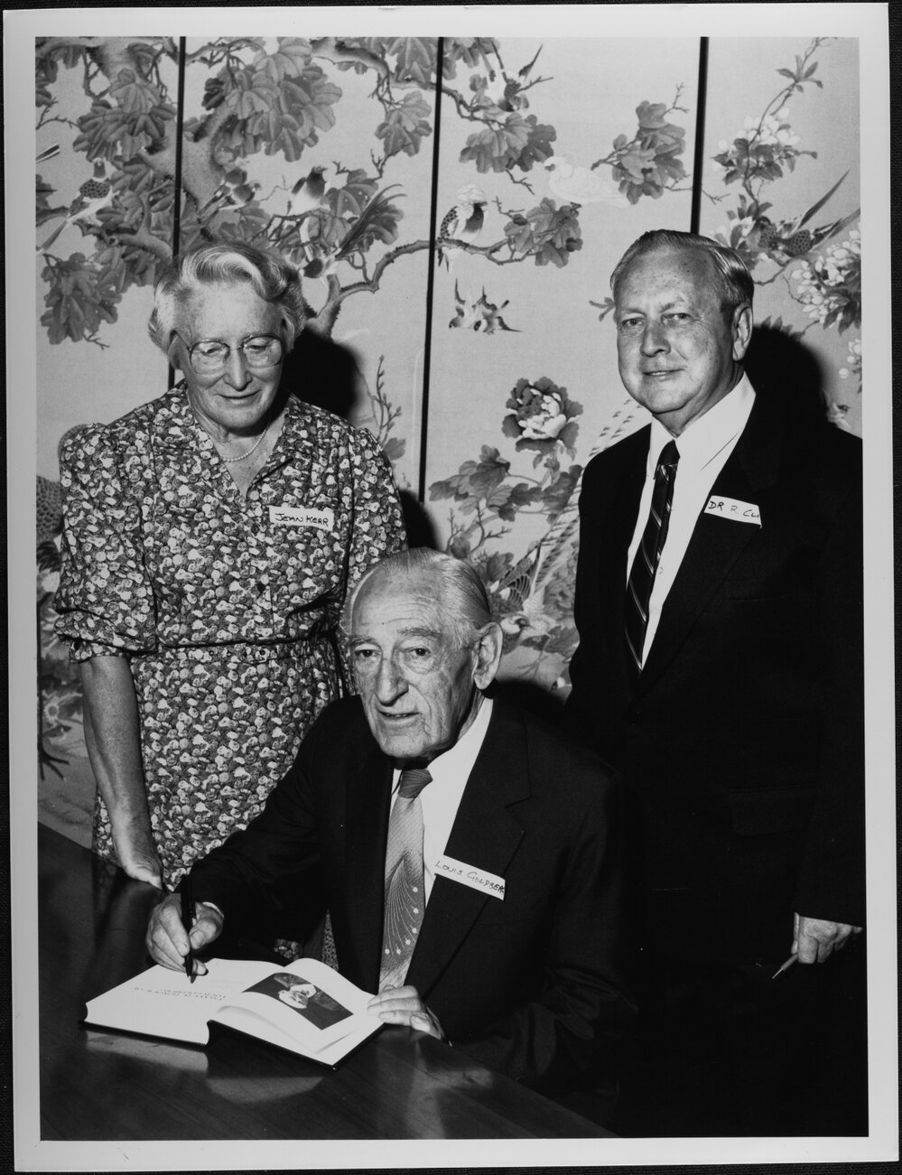 Goldberg, Professor Emeritus Louis, signing a copy of &lsquo;Essays in Honour of Louis Goldberg&rsquo; launched at University House. Included are Miss Jean Kerr, former Reader in Accounting and Dr Bob Clift, Reader in Accounting, who edited the essays