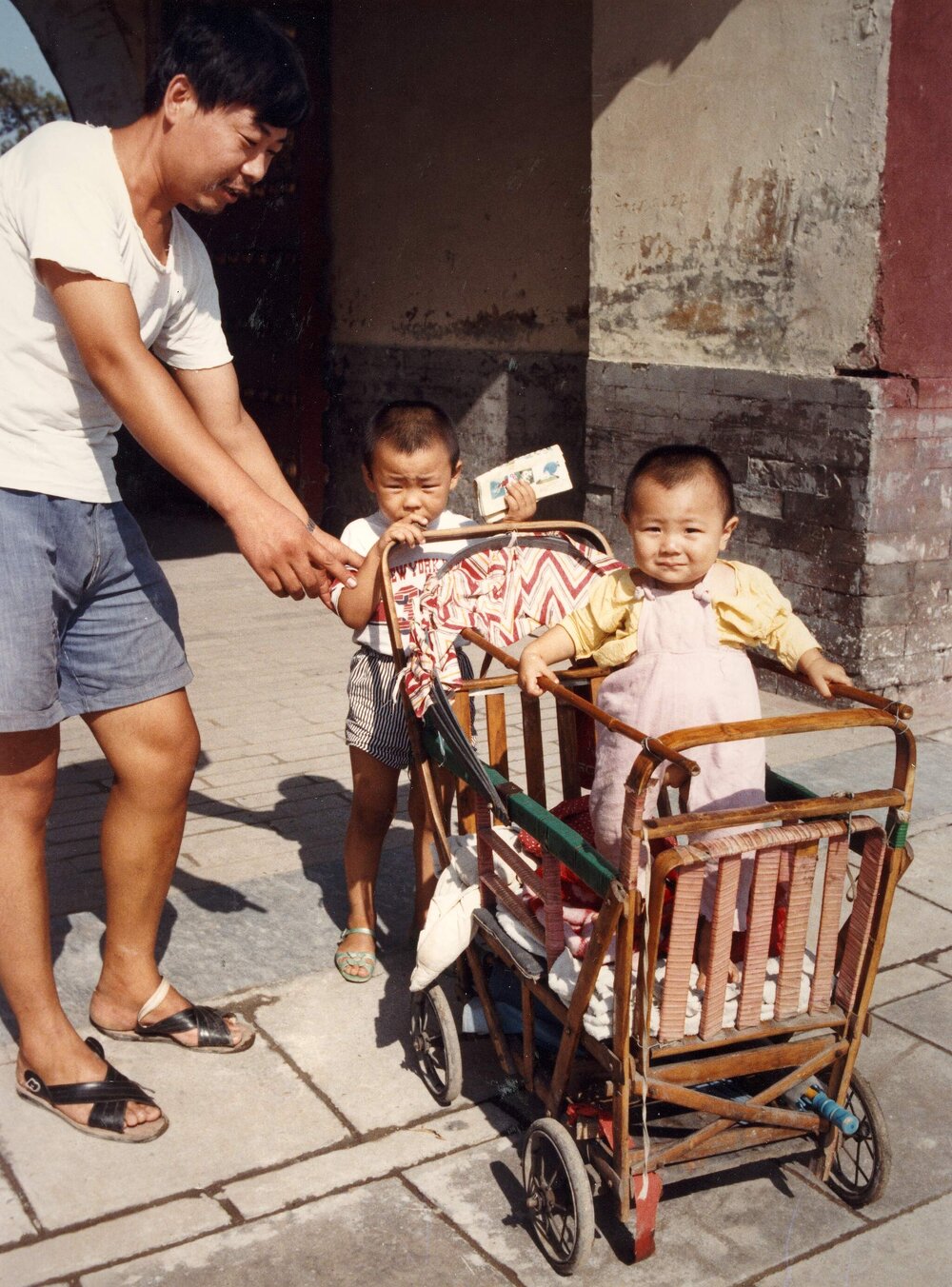 A street scene in Beijing, China, showing a Chinese man with two young children.
