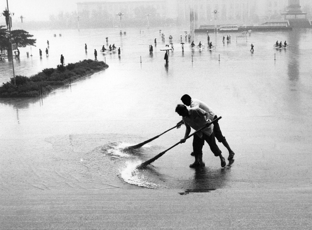 Men sweeping rainwater in Tiananmen Square, Beijing, China.
