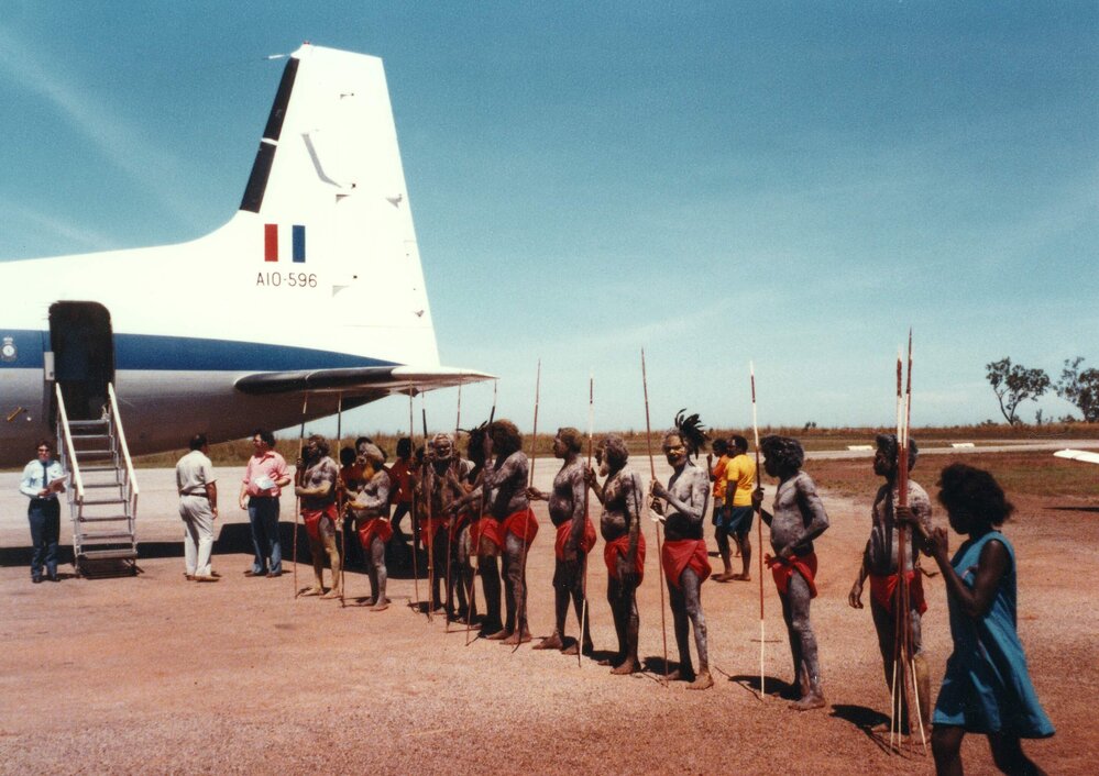 A group of welcoming Aboriginal Australians standing alongside a Royal Australian Air Force aircraft in the Northern Territory.