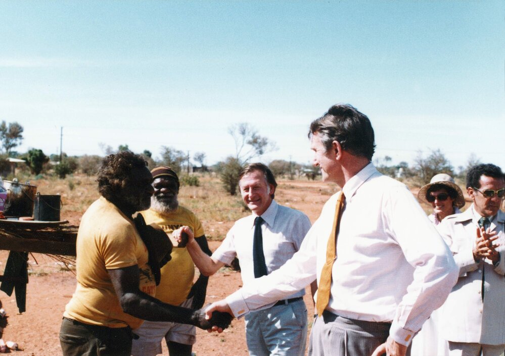 Malcolm Fraser greeting an Aboriginal Australian man at a settlement in the Northern Territory.