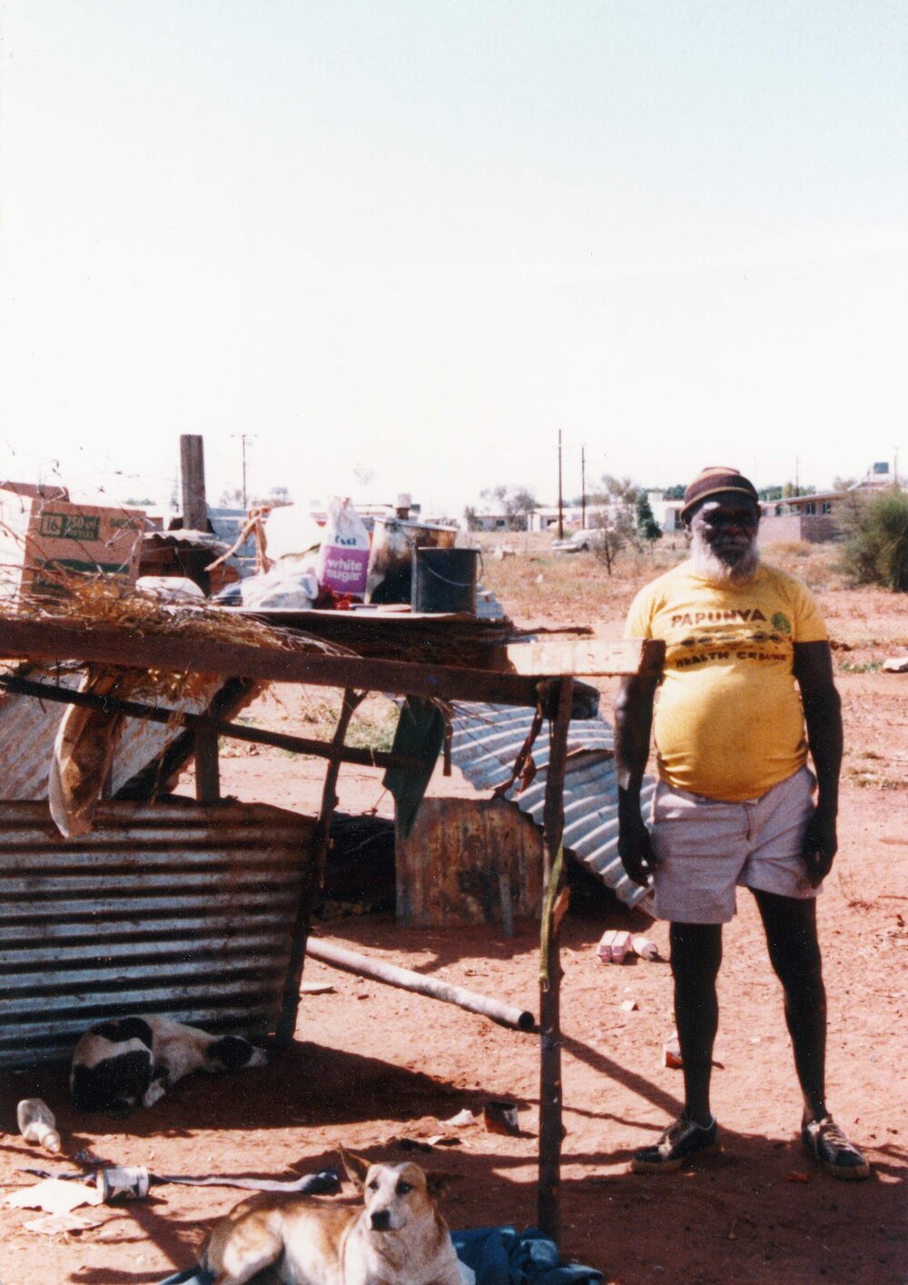 An Aboriginal Australian man standing alongside a dwelling in the Northern Territory.