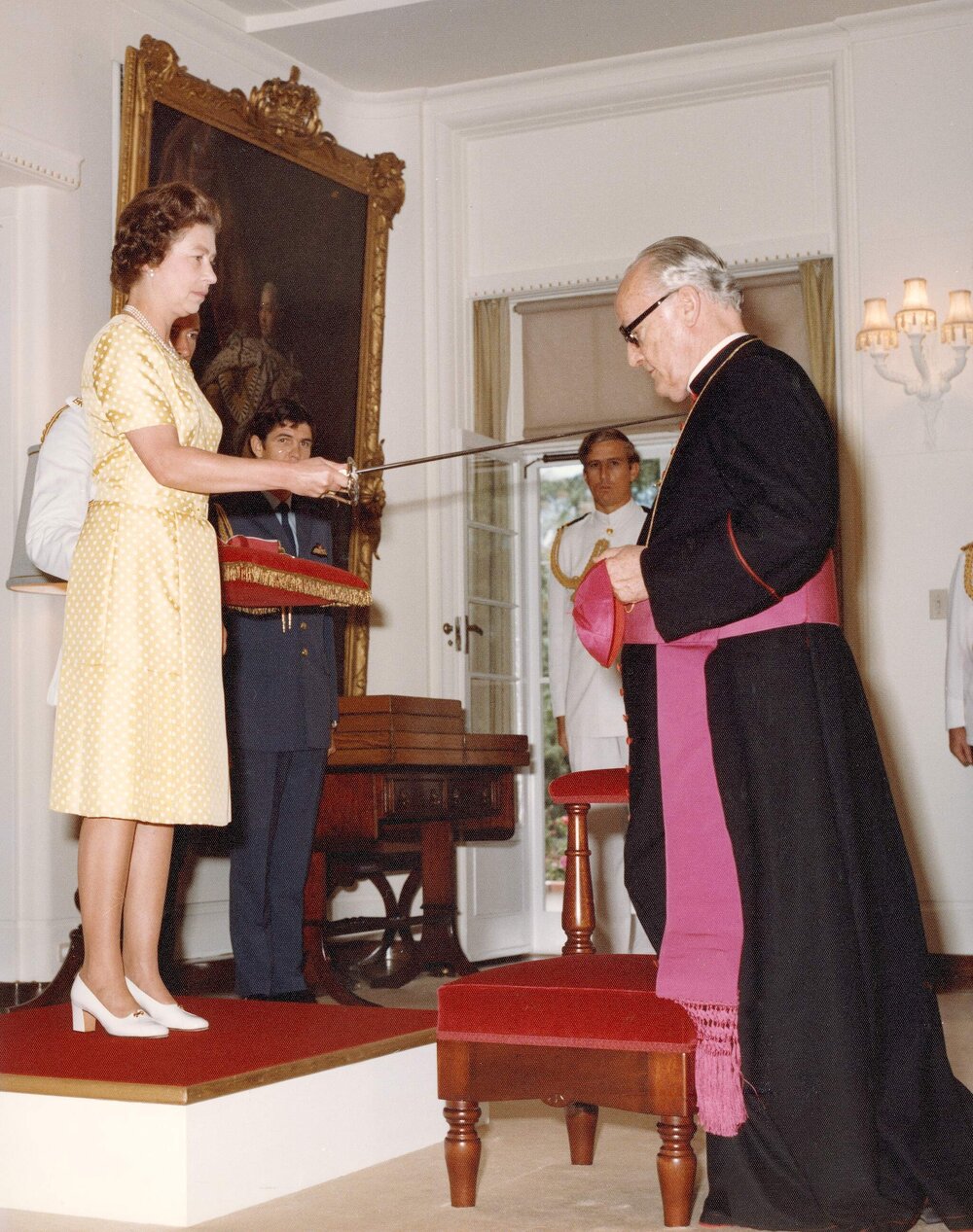 Queen Elizabeth II knighting a cardinal of the Roman Catholic Church at Government House Canberra, Australian Capital Territory.