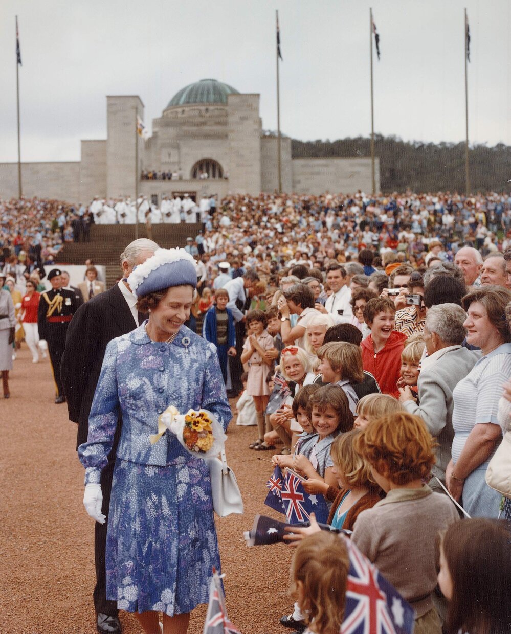 Queen Elizabeth II greeting children at the dedication of a memorial for the Royal Regiment of Australian Artillery in Canberra during her 1977 official visit to Australia.
