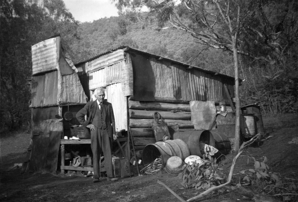 Man in bushland setting in front of a dwelling