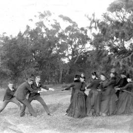 Group of men and women playing "tug of war"