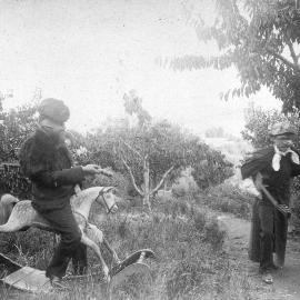 Photo of two children playing outdoors, one on rocking horse