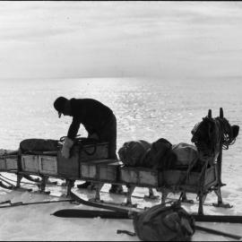 J. M. Scott lashing up sledge in the evening, Ivigtut journey