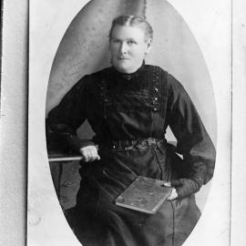 Portrait of an unidentified seated woman holding a book.