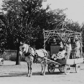 An open car decorated with flags and carrying girls dressed as fairies.