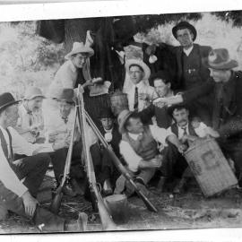 A group of unidentified young men relaxing and drinking under a tree.