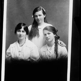 Studio portrait of three unidentified young women dressed in white.