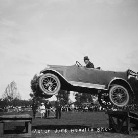 A car being driven across a gap between two timber ramps at the Benalla Show in 1921.