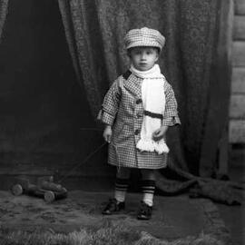 Studio portrait of a young Master Bell dressed in a hat and coat.