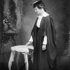Studio portrait of Miss M. Cailin wearing an academic gown.