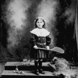 Studio portrait of young girl holding a racquet..