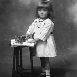 Portrait of an unidentified young girl holding a toy cat.