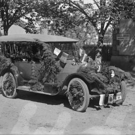 A car decorated with spruce or fur branches and flags of many nations.