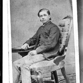 Portrait of an unidentified young man seated at a round table.