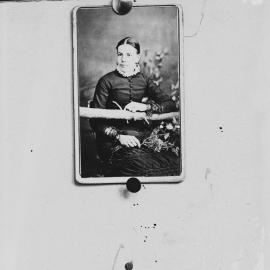 Studio portrait of an unidentified young woman resting on a tree branch.