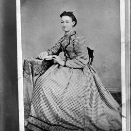 Portrait of a seated woman wearing a patterned dress.