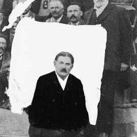 A group of men.  One unidentified man has been masked out from the rest.