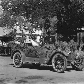 A car decorated with wheat and carrying several women.