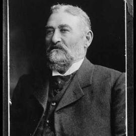 Studio portrait of a bearded man wearing a high collared shirt.