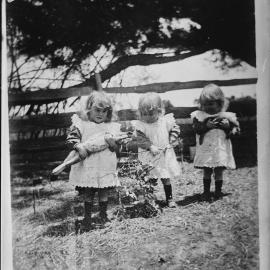Three unidentified small girls in an outdoor location.