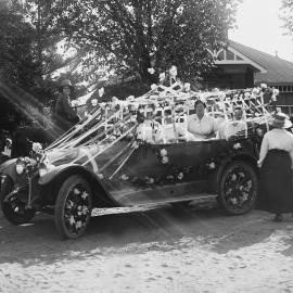 An open car, heavily decorated with flowers and streamers, and carrying several women.