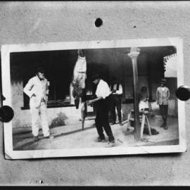 A man workng under a shop verandah.