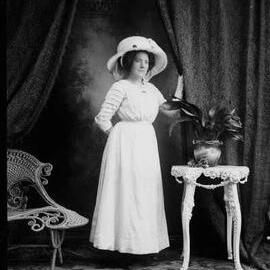 Studio portrait of Miss Lily Pretty wearing a large hat.