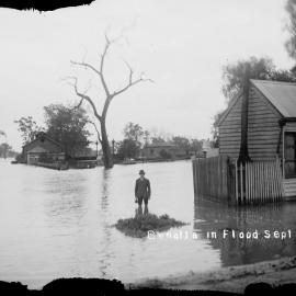 A man standing in flood waters alongside a small timber dwelling in Benalla.
