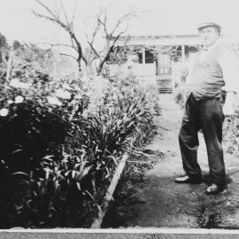 An unidentified man standing on a path in a garden.